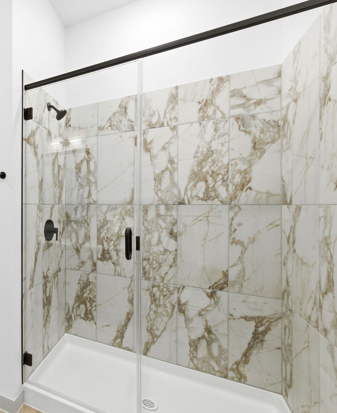 Wixby House Modern bathroom with a glass shower and marble tile, adjacent to a carpeted bedroom.
